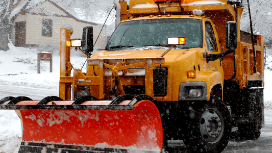 Heavy-duty snow plow blade attached to a truck removing snow from a residential street, showing how to choose the right plow blade for Kentucky winter conditions.