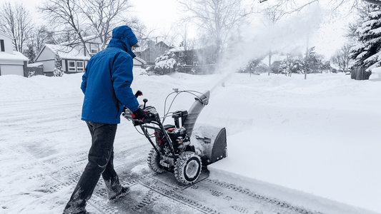 Operator using snow removal equipment to clear a driveway during a winter storm, representing trusted snow plow equipment available in Somerset, KY.
