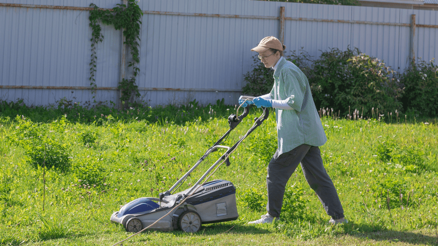 Homeowner mowing grass with a walk-behind mower, highlighting top mowers available in Somerset, KY from Southeastern OPE.